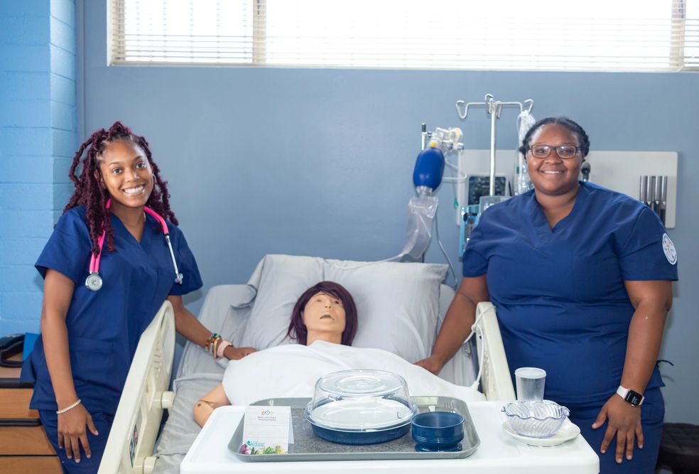 Two people beside a mannequin in a skills training room